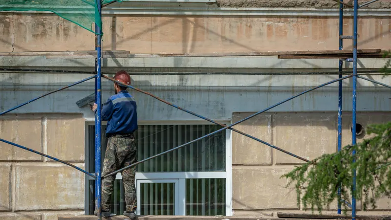 Radnik na skeli izvodi završni sloj fasade